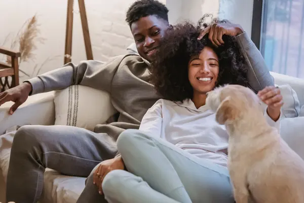 Pareja joven jugando con su perro en el sofá